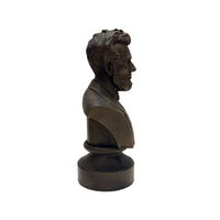 A side profile view of the bronze colored statue of the head of Abraham Lincoln up to the torso