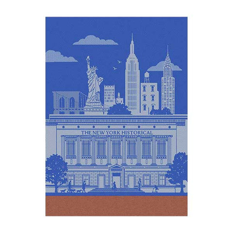 A kitchen towel featuring the design of The New York Historical Facade Building in blue and white with New York City's iconic skyline in the background and an orange border towards the bottom