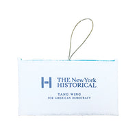 A white rectangular fabric ornament on a thin hanging loop at the top, printed with the New York Historical logo and the text 'TANG WING FOR AMERICAN DEMOCRACY' in blue