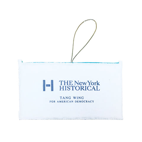 A white rectangular fabric ornament on a thin hanging loop at the top, printed with the New York Historical logo and the text 'TANG WING FOR AMERICAN DEMOCRACY' in blue