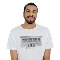 Man wearing a white unisex t-shirt with the design of The New York Historical Building Facade with the text under the design 