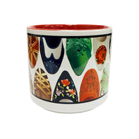 A front view of a white ceramic mug featuring a variety of illustrated designs of the front of shoes and heels. The interior of the mug is red.