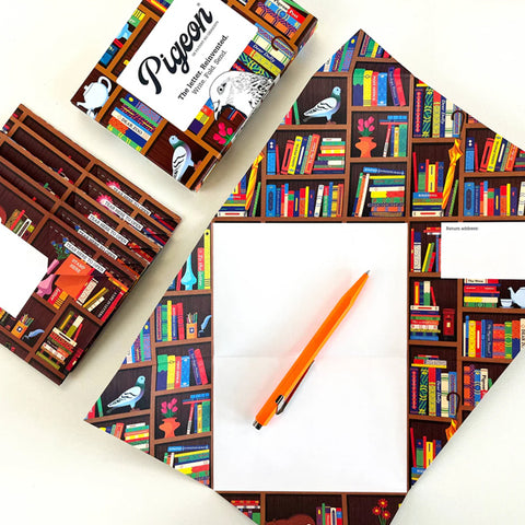 A cropped image of an array of materials spread as a top-down view. The packaging box of the letters and envelopes of the same design is placed towards the top while the letter and a pencil is placed below the frame