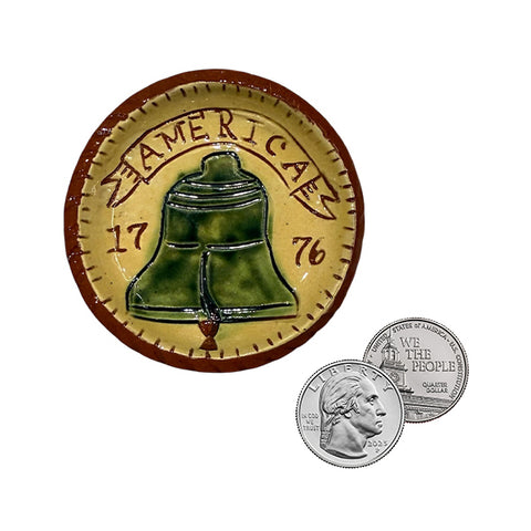 miniature red terracotta plate with a bell in the center and the text 