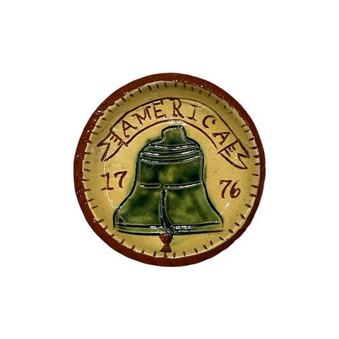 miniature red terracotta plate with a bell in the center and the text 