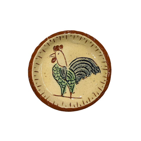 miniature terracotta plate with a drawing of a chicken in the middle with lines around the rim