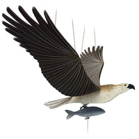 A wooden mobile of a white and brown osprey bird with spread wings and a small fish dangling below