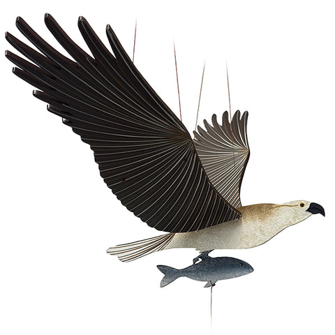 A wooden mobile of a white and brown osprey bird with spread wings and a small fish dangling below