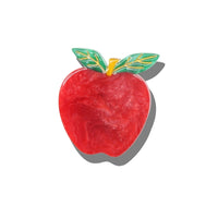 A red apple-shaped enamel pin with green leaves and a yellow stem