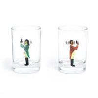 Two clear shot glasses on a white background, each printed with a small illustration of men in time-period clothing
and black text.