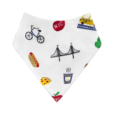 A front view of a white triangular bandana bib featuring a colorful New York City-themed print with illustrations of a bicycle, hot dog, pizza, coffee cup, bridge, taxi, and red NYC logos.