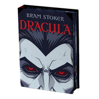 A front view of the book light of Bram Stoker's Dracula, shown at a three-quarter angle on a plain white background. The cover features a stylized illustration of Dracula's face with pale gray skin, black hair, and piercing red eyes, with the title 'DRACULA' in bold red letters.