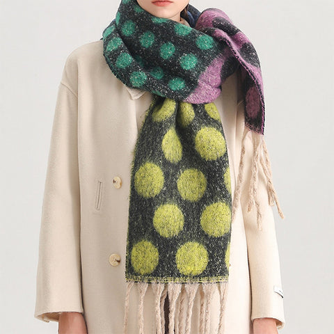 Person wearing a polka dot scarf with green, purple, and yellow colors on a plain background.