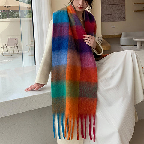 A woman wearing a beige coat, a color spectrum patterned scarf on a white background