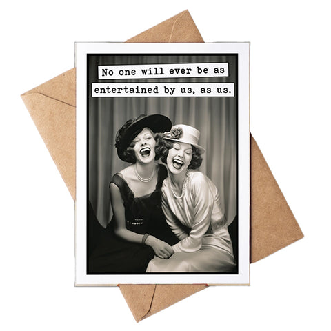 A greeting card with a white border and a black-and-white photo of two laughing women, with text at the top reading, 'No one will ever be as entertained by us, as us.' A kraft paper envelope is placed behind the card on a white background.