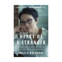 Book cover of 'Heart of a Stranger' by Angela Buchdahl, featuring a portrait of the author with glasses and a white shirt, with white title text on a muted blue-gray background.