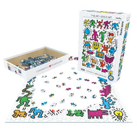 A colorful puzzle set is shown with its illustrated box, an open box of puzzle pieces, and a partially assembled puzzle on a white background. The artwork features playful cartoon figures in bright, multicolored tones by Keith Haring.